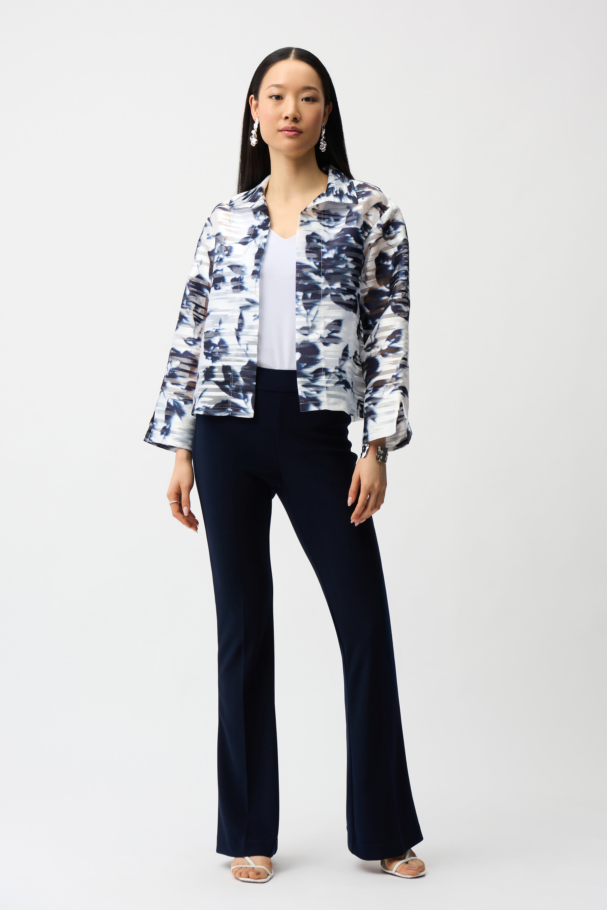 Woman wearing blue and white abstract print jacket with structured fit, styled with white top and navy pants, full outfit studio look on white background