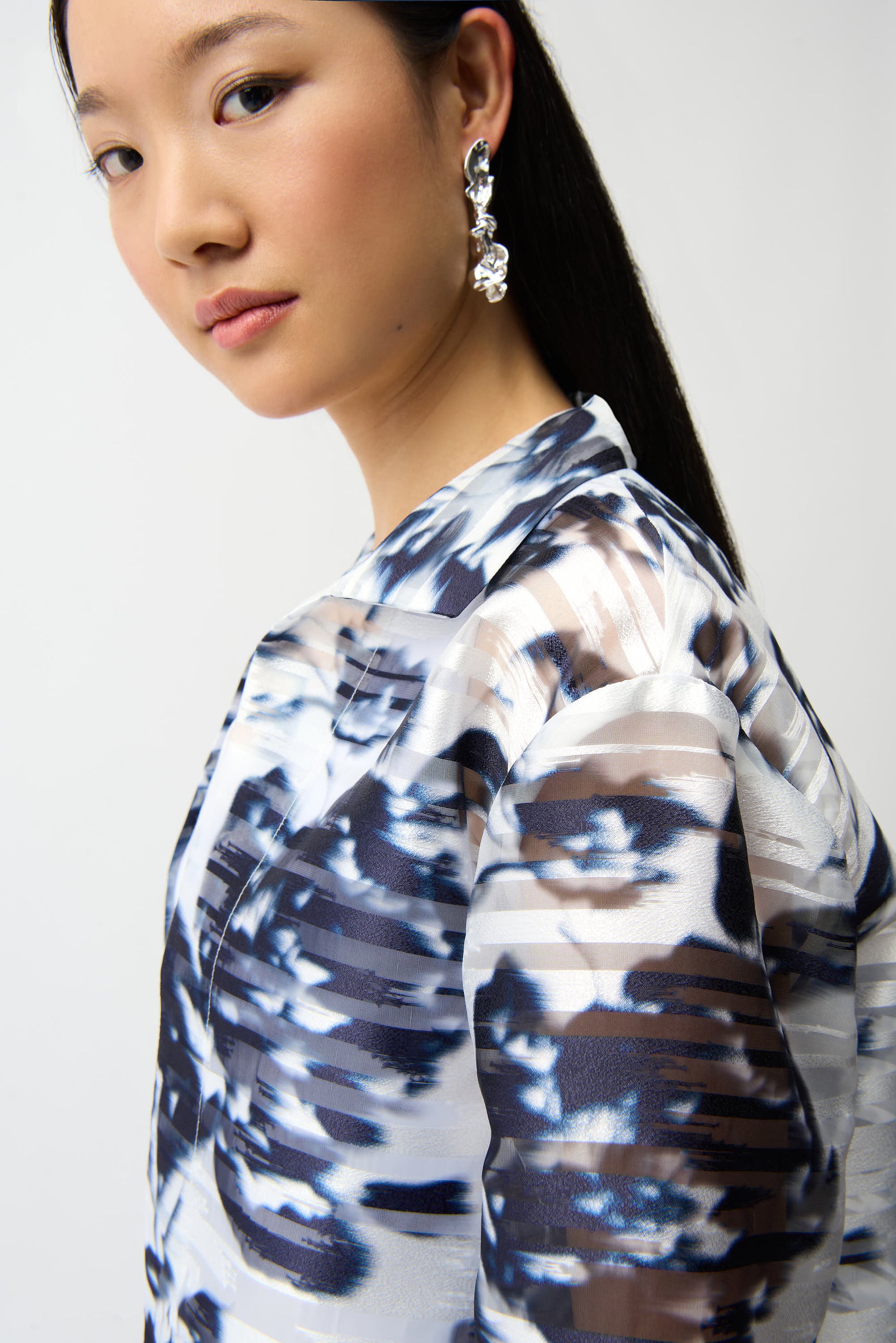 Close-up side view of blue and white abstract print jacket showing textured fabric and structured collar detail, studio shot on white background