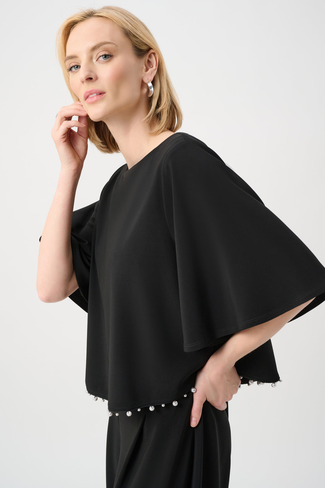 Women’s black silky knit flared top with pearl detail hem and wide sleeve design