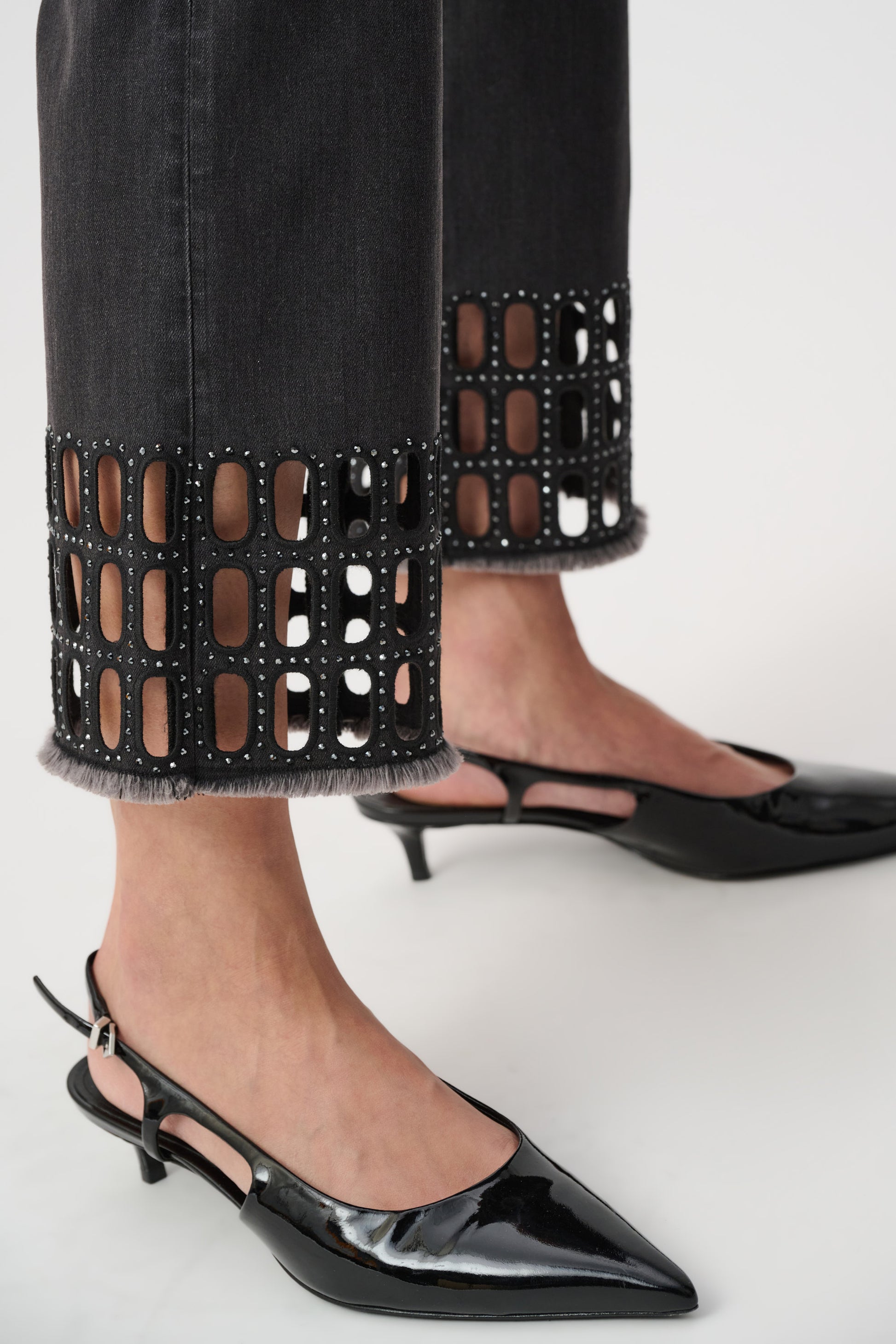Black jeans cut-out hem detail close-up with pointed heels