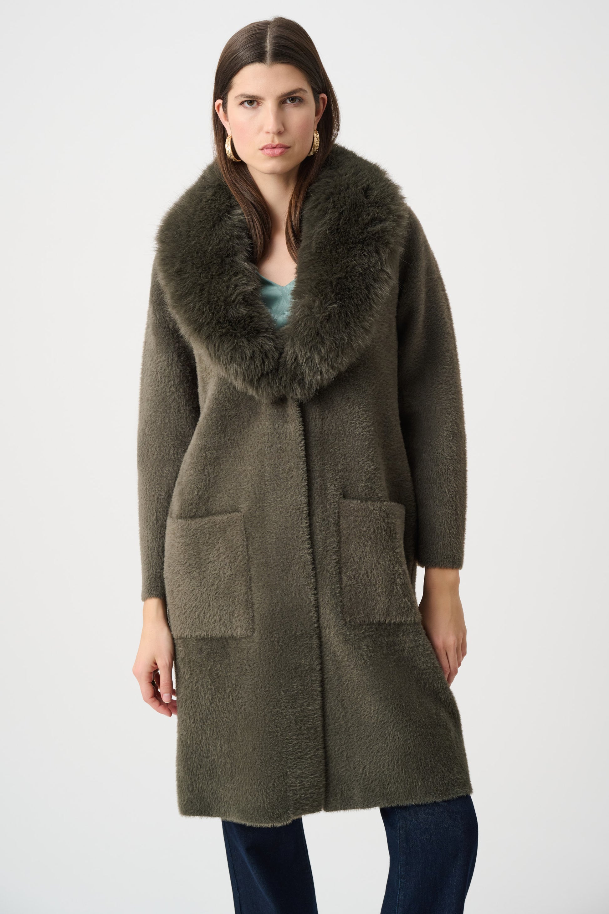Detailed view of beige coat fur collar and patch pockets on white background