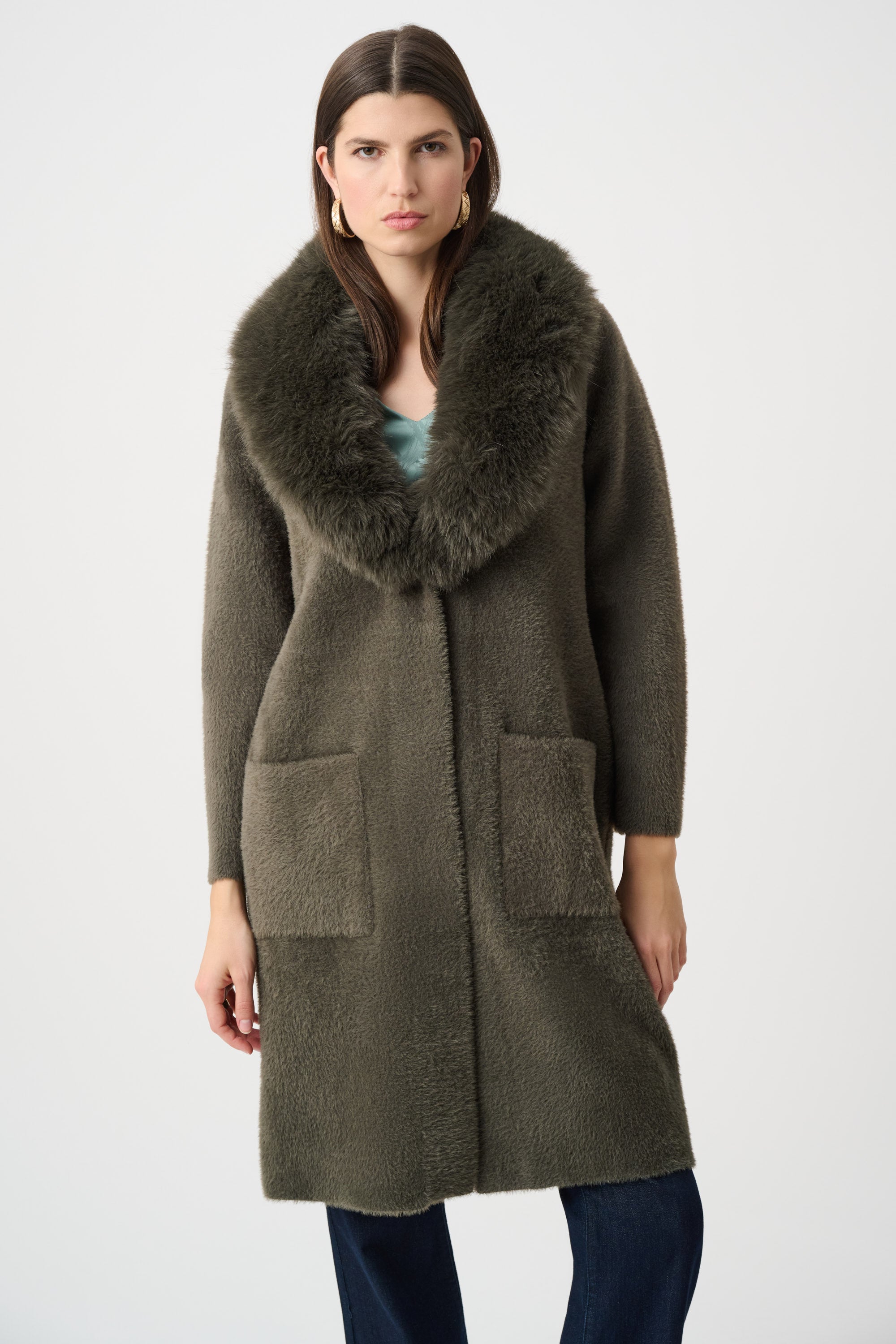 Detailed view of beige coat fur collar and patch pockets on white background