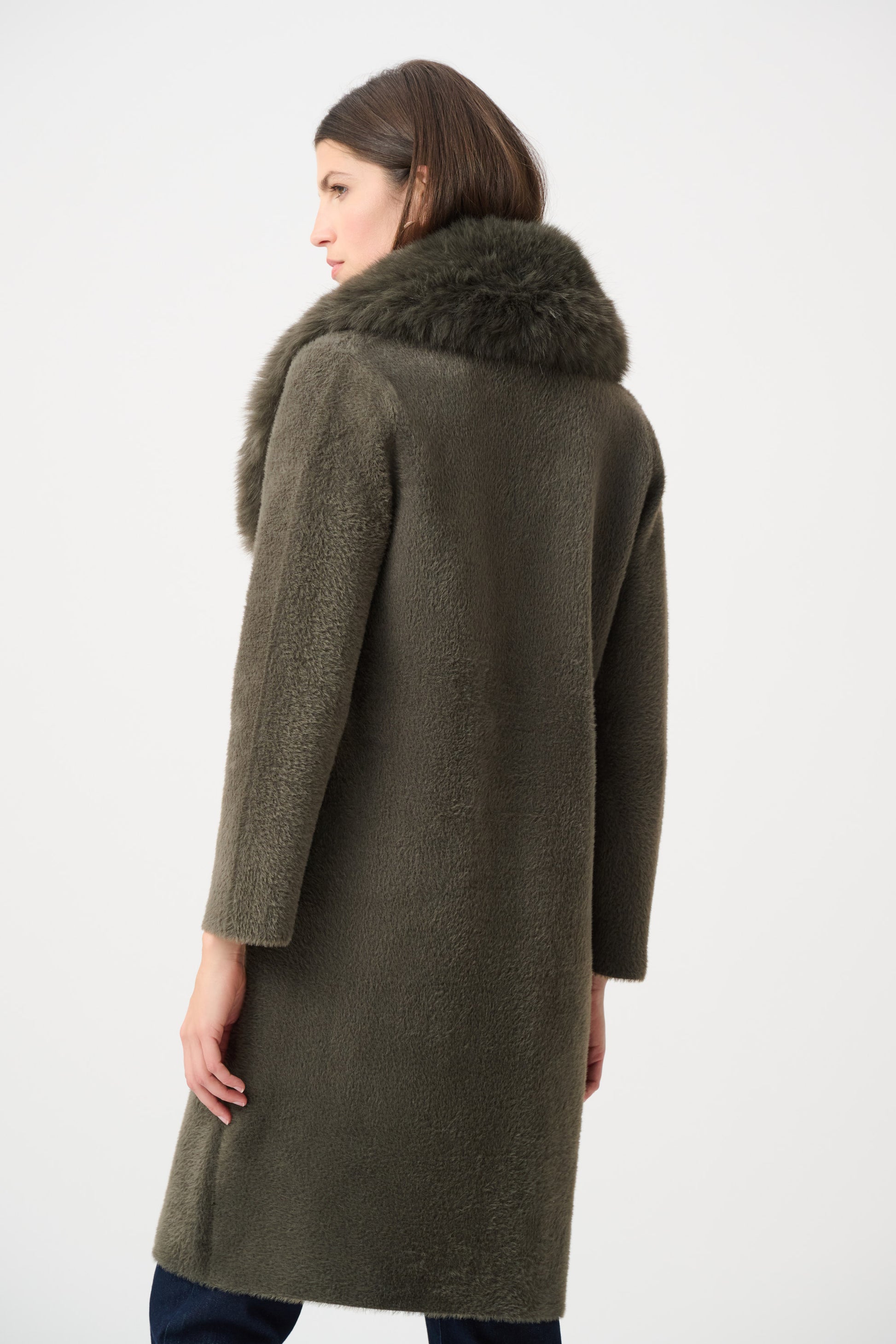 Woman wearing beige coat with fur collar in indoor setting