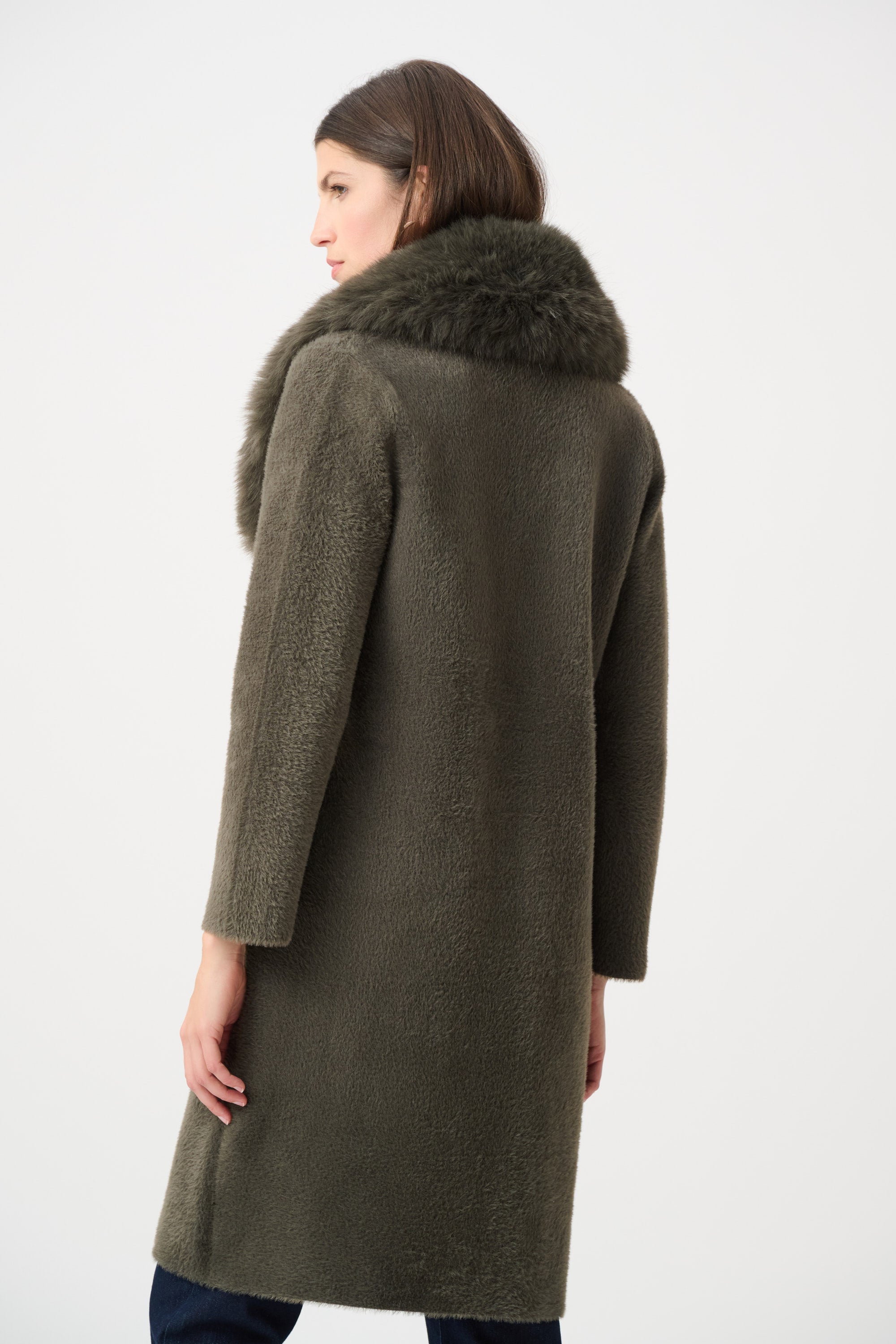 Woman wearing beige coat with fur collar in indoor setting