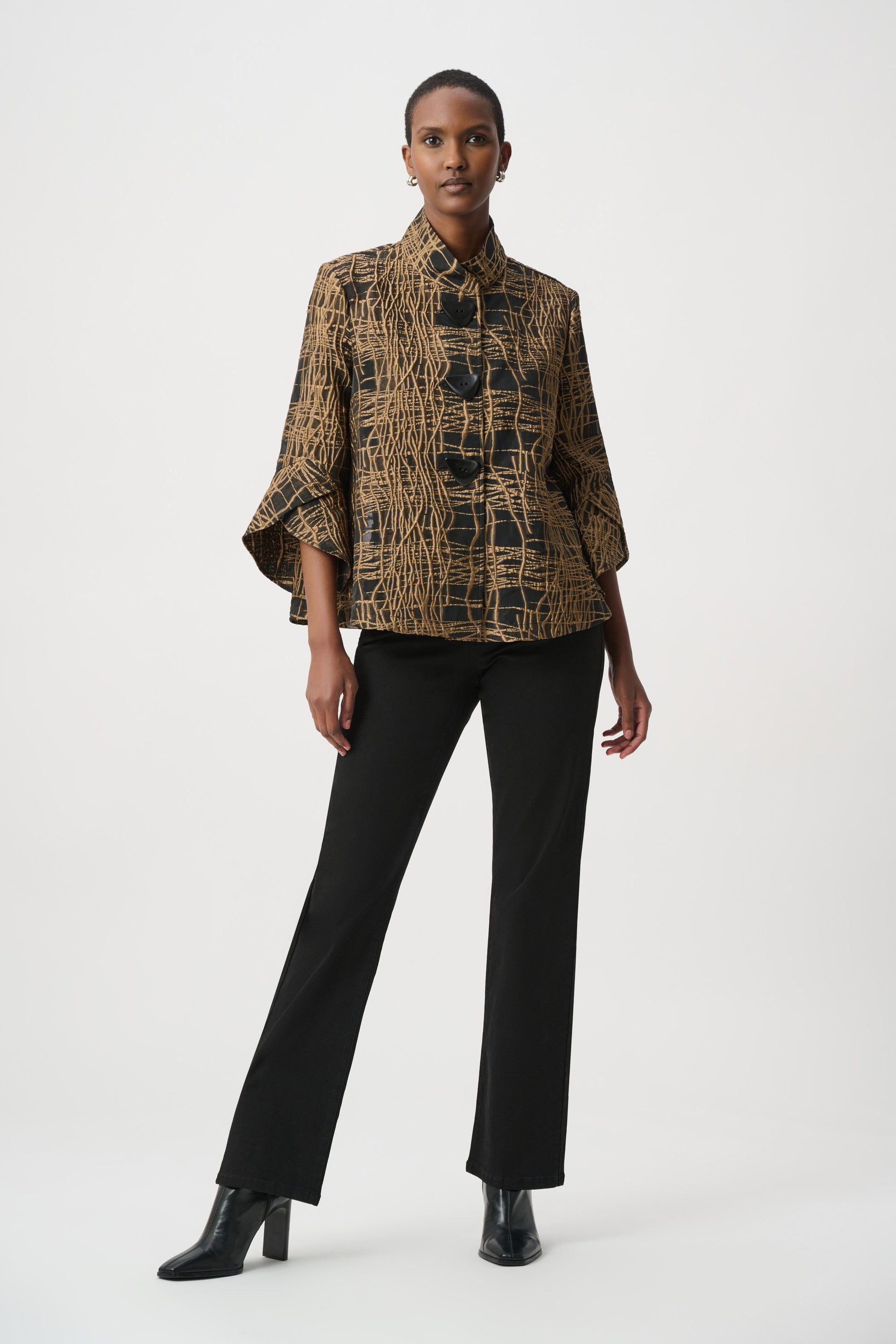 Woman wearing a cropped black and tan abstract patterned jacket with decorative buttons