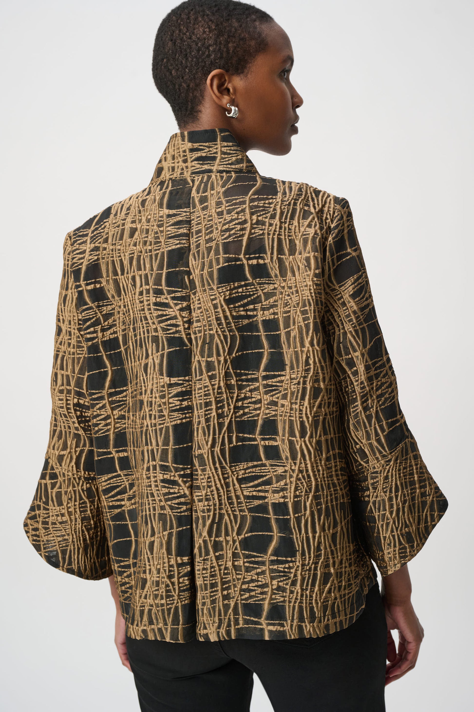 Woman wearing a high-neck black and tan jacket from the back