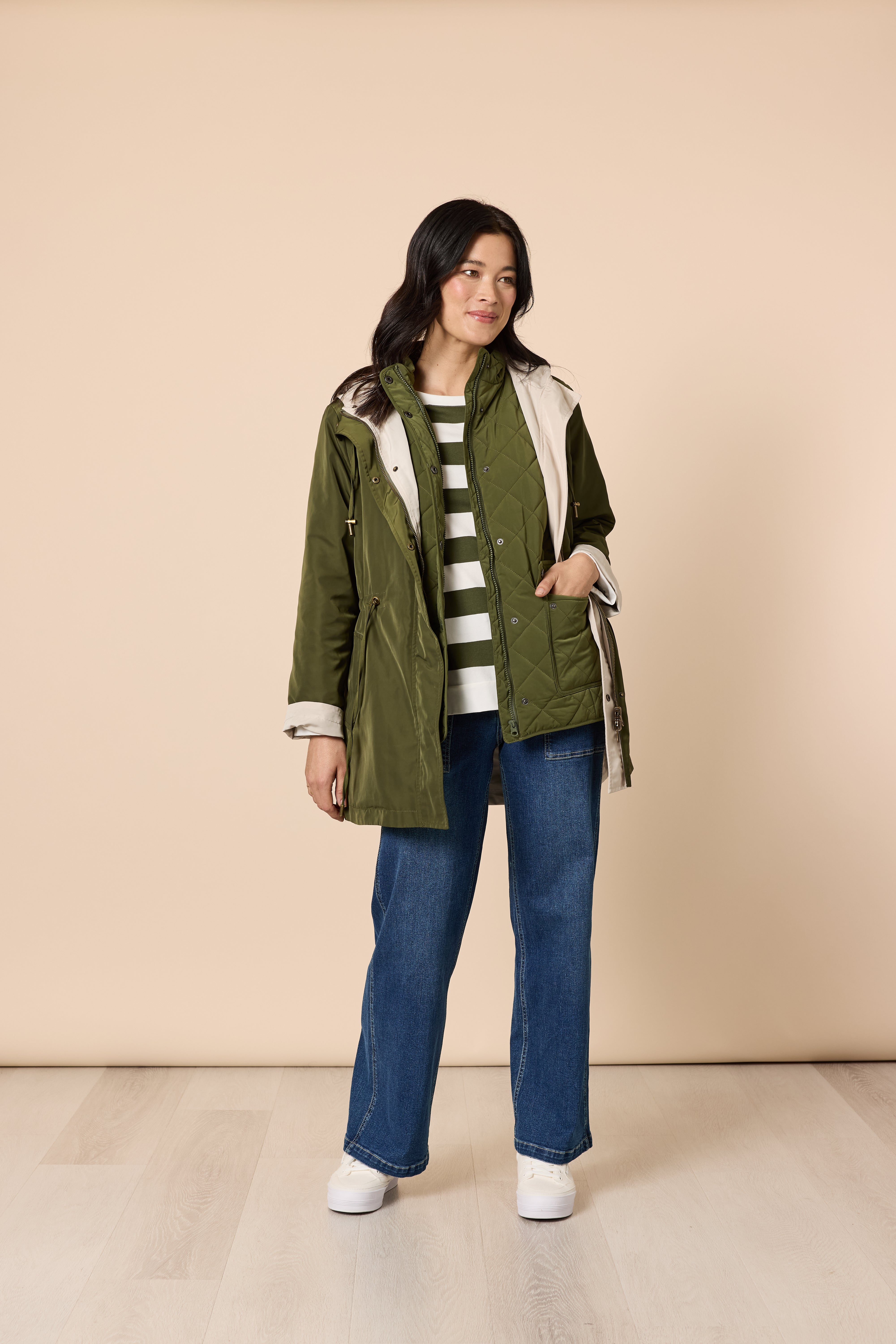 Model wearing green utility jacket over striped sweater with relaxed fit jeans