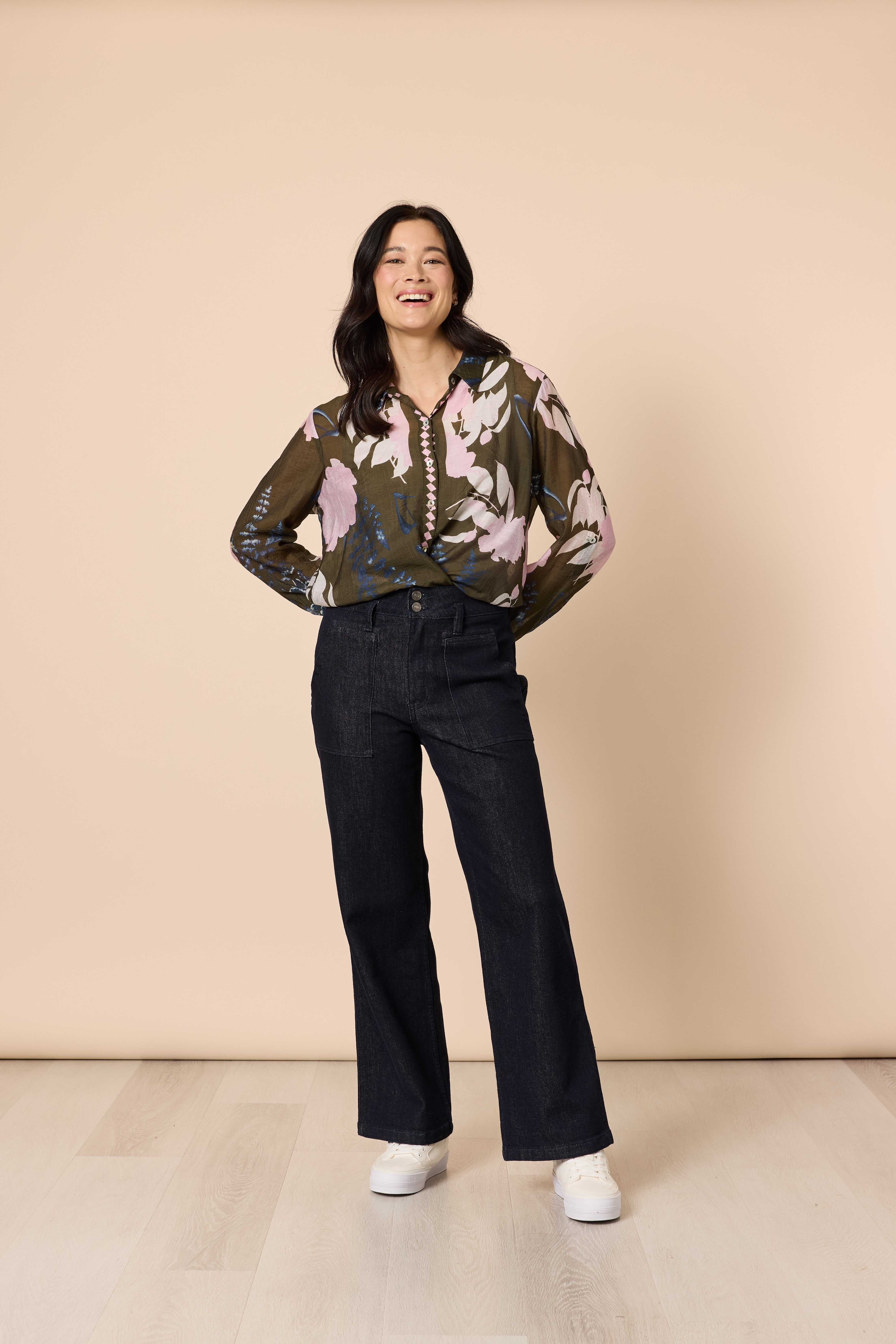Woman in khaki floral blouse and dark denim wide leg jeans front pose