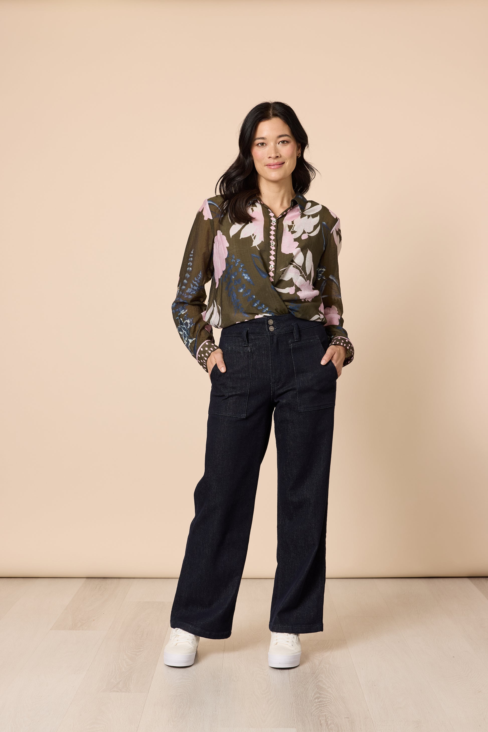 Casual outfit woman wearing printed khaki top with dark denim jeans hands in pockets