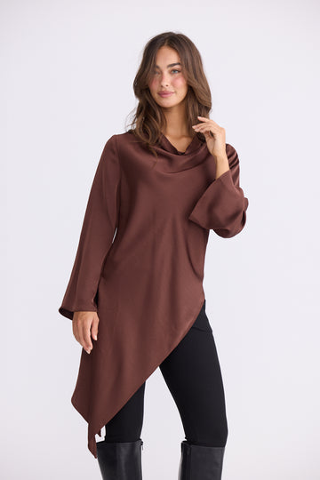 Woman wearing chocolate brown asymmetric drape top with relaxed fit on white background