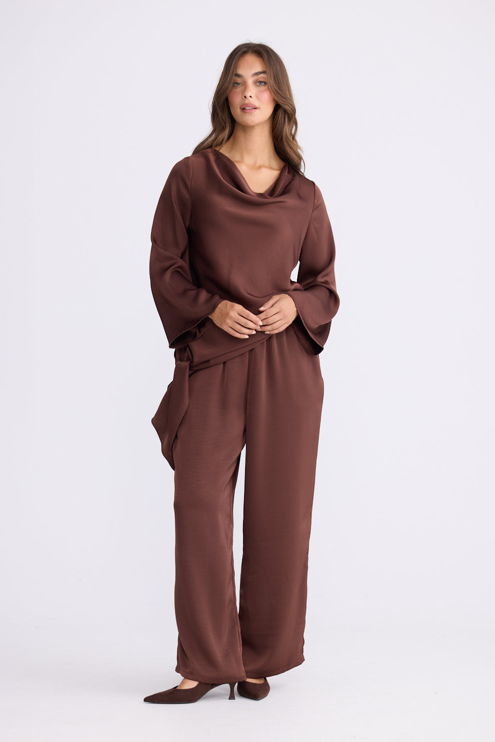 Woman wearing chocolate drape top styled with matching relaxed pants on white studio background