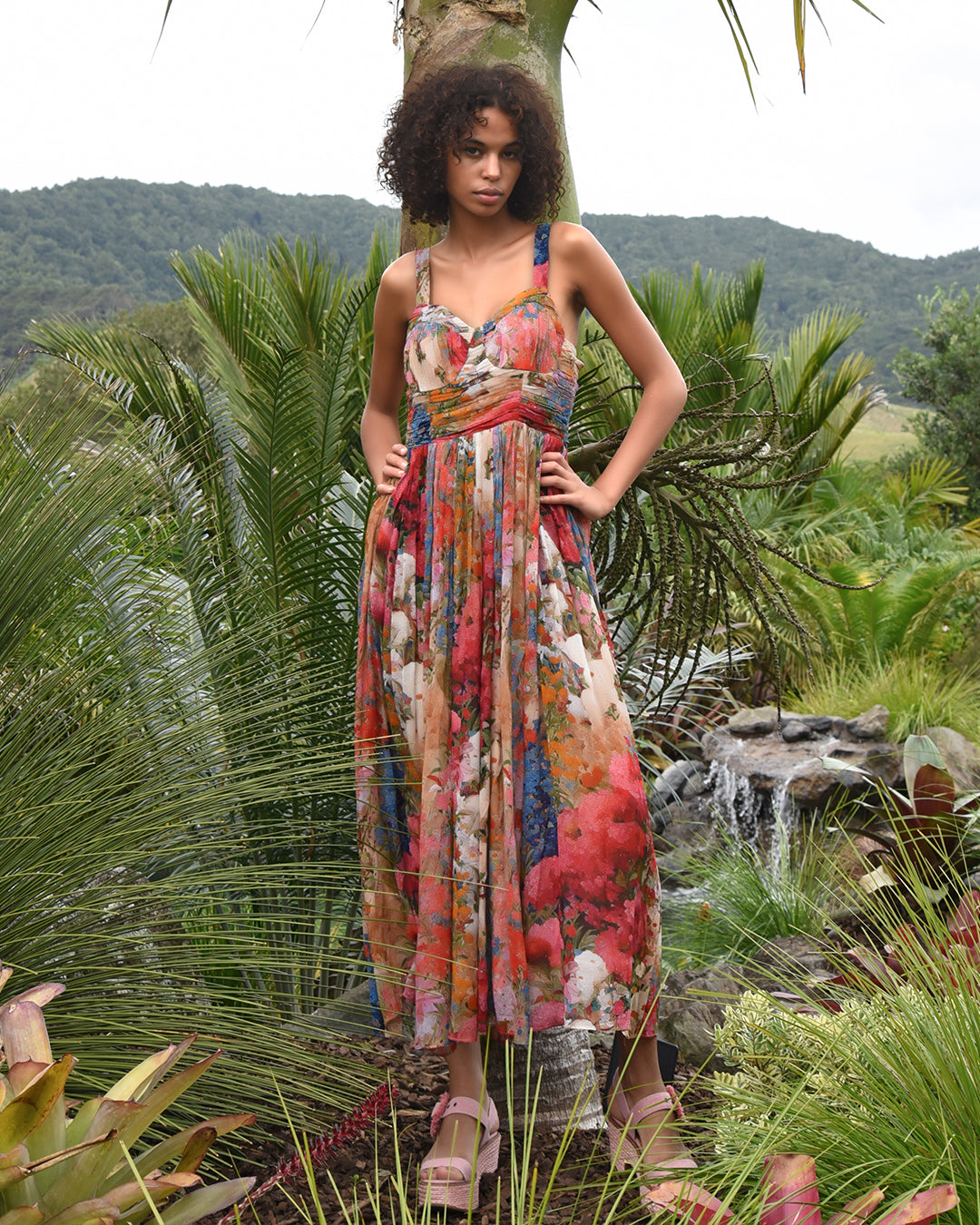 Multicolour floral maxi dress with ruched waist in tropical garden setting.