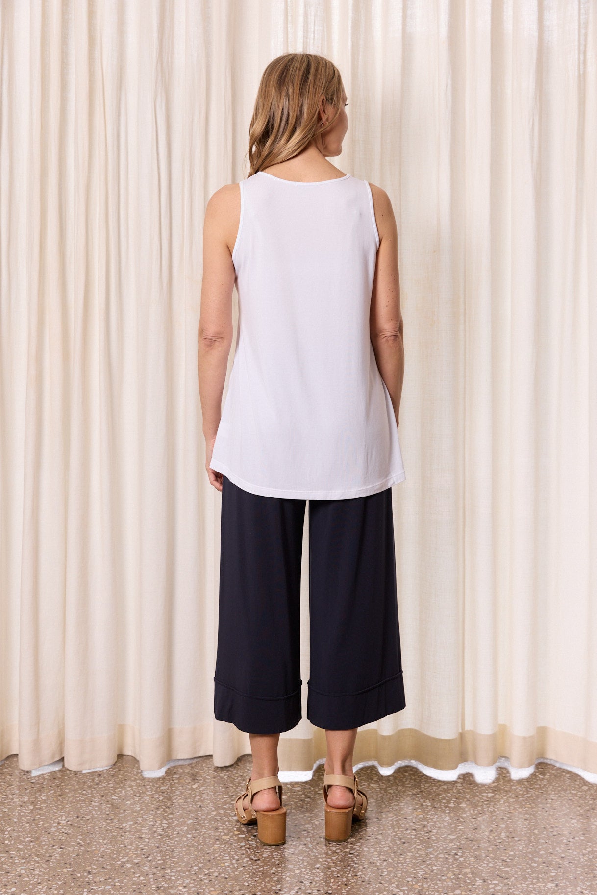 Back view woman wearing white sleeveless top and wide leg pants casual outfit