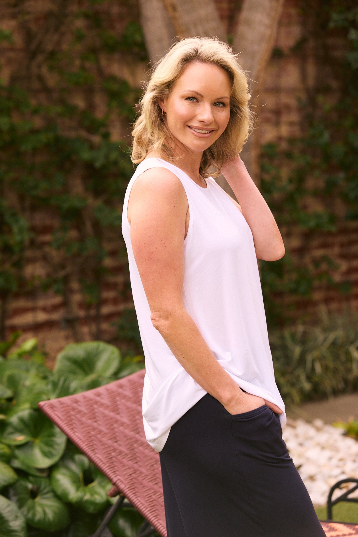Woman in white sleeveless top and black pants outdoor casual summer outfit
