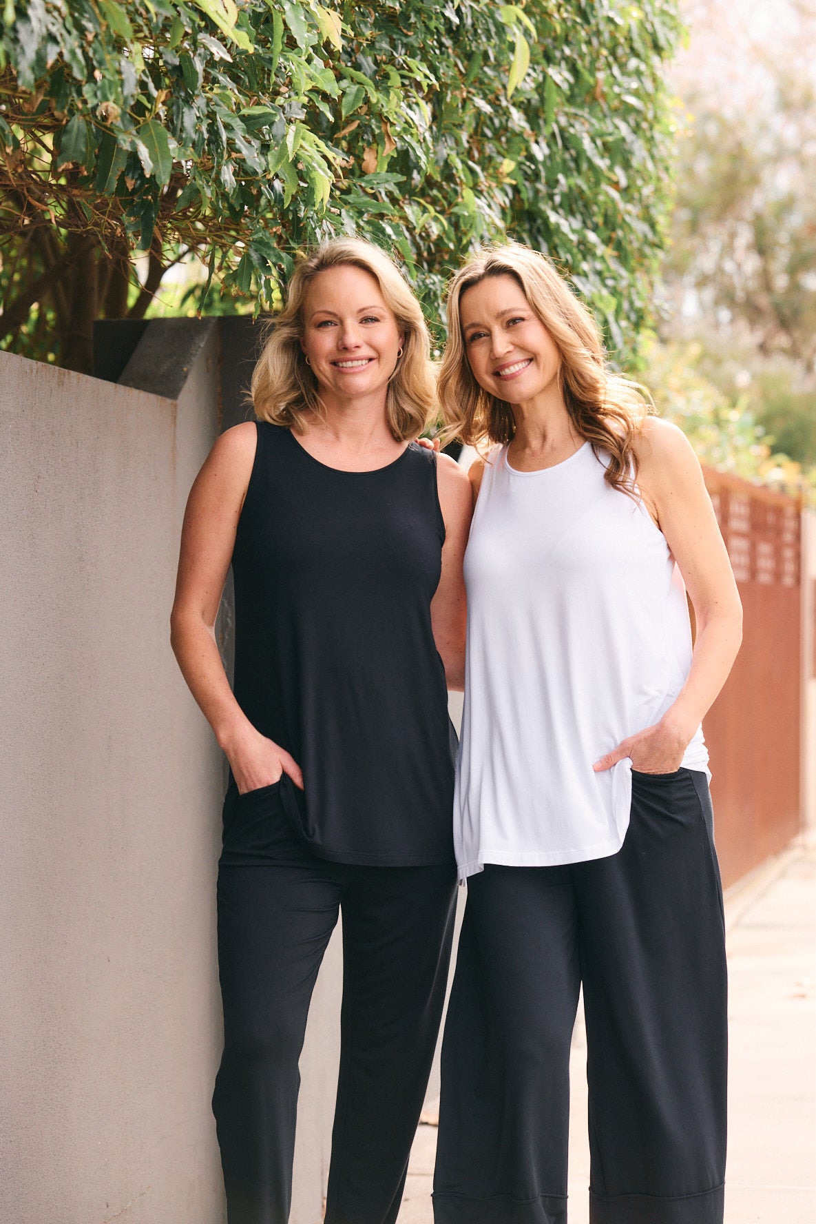 Two women standing outdoors in coordinated casual outfits relaxed fashion look