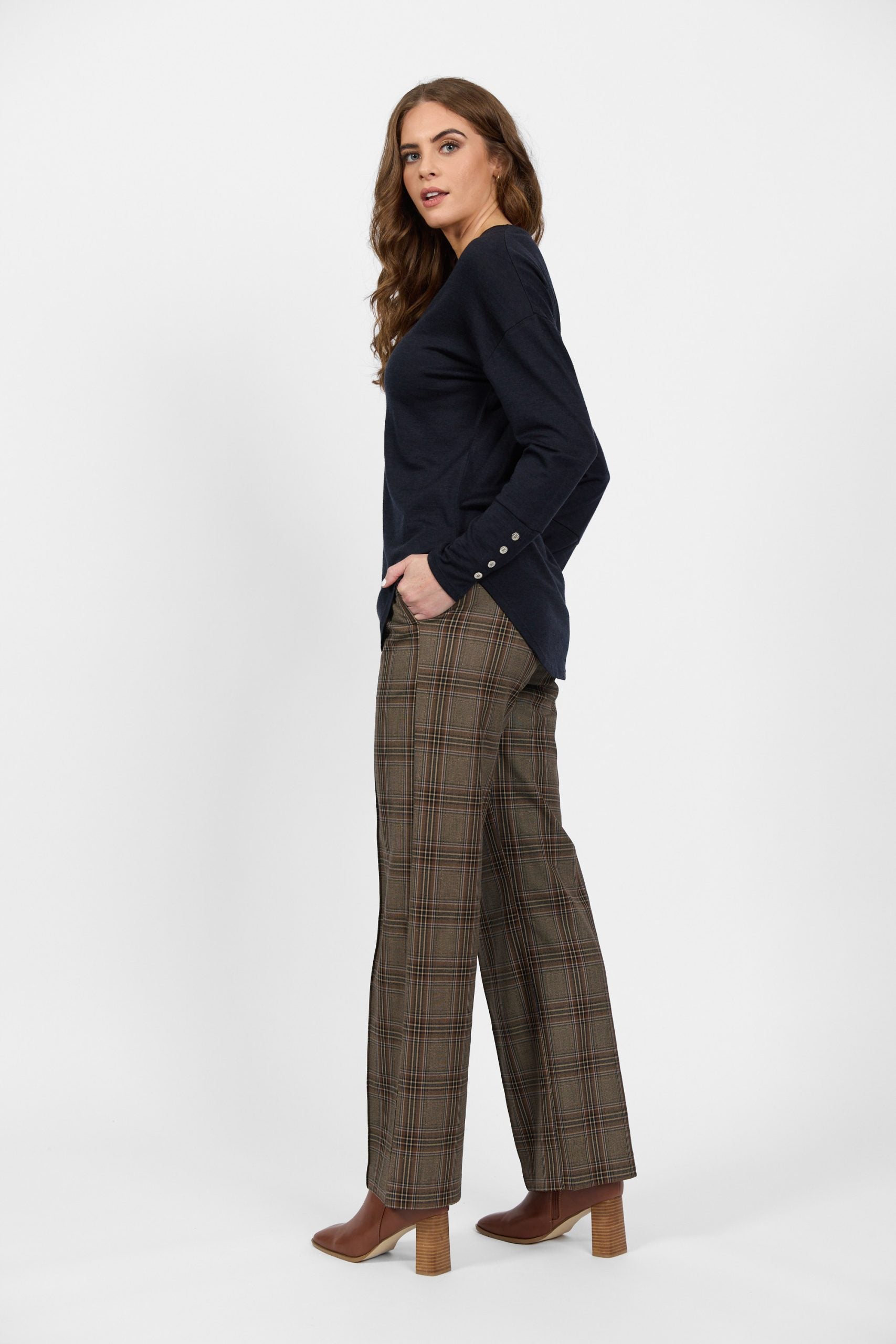 Side view of navy merino top with button cuffs and plaid trousers