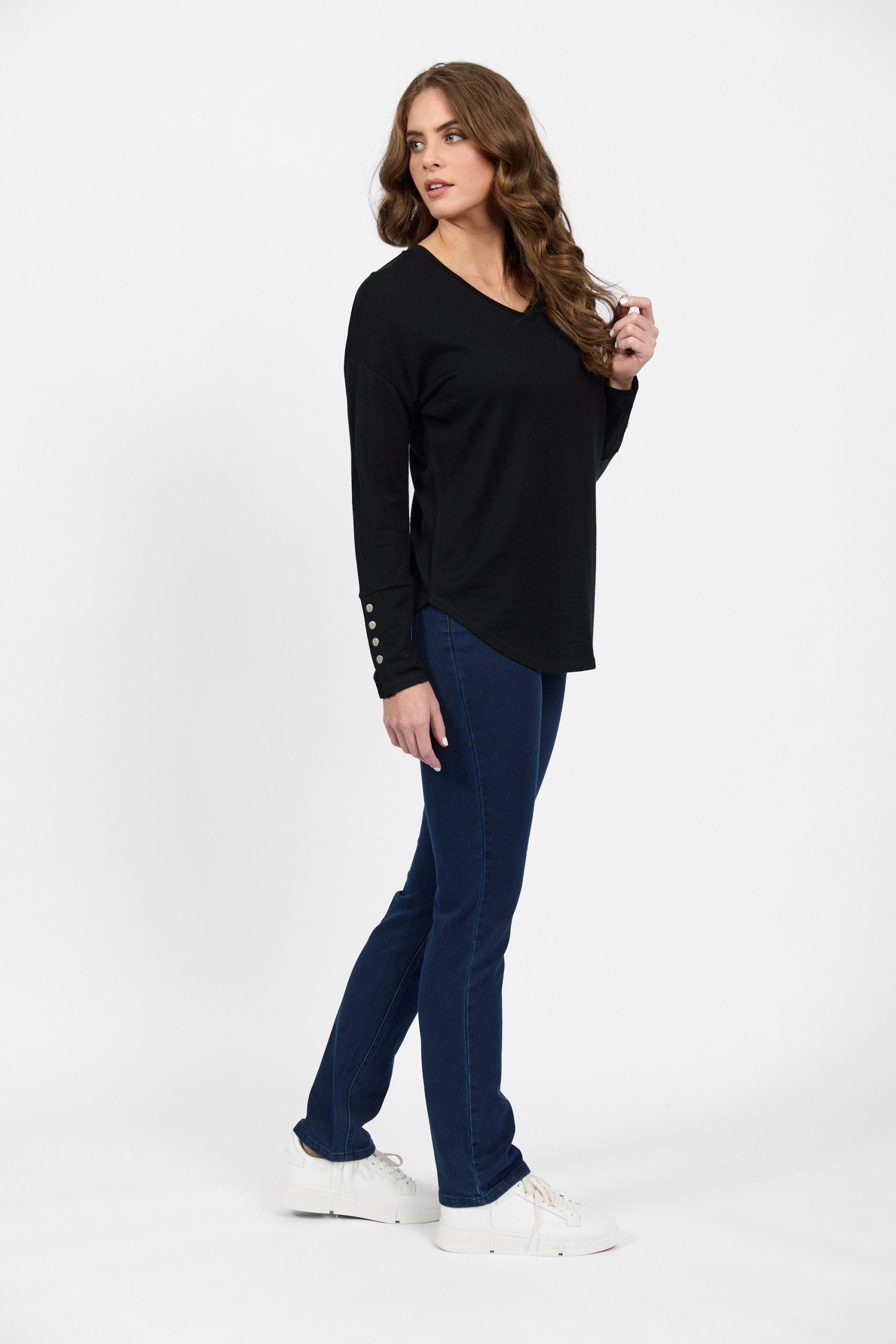 Side profile of black merino knit top with blue denim jeans