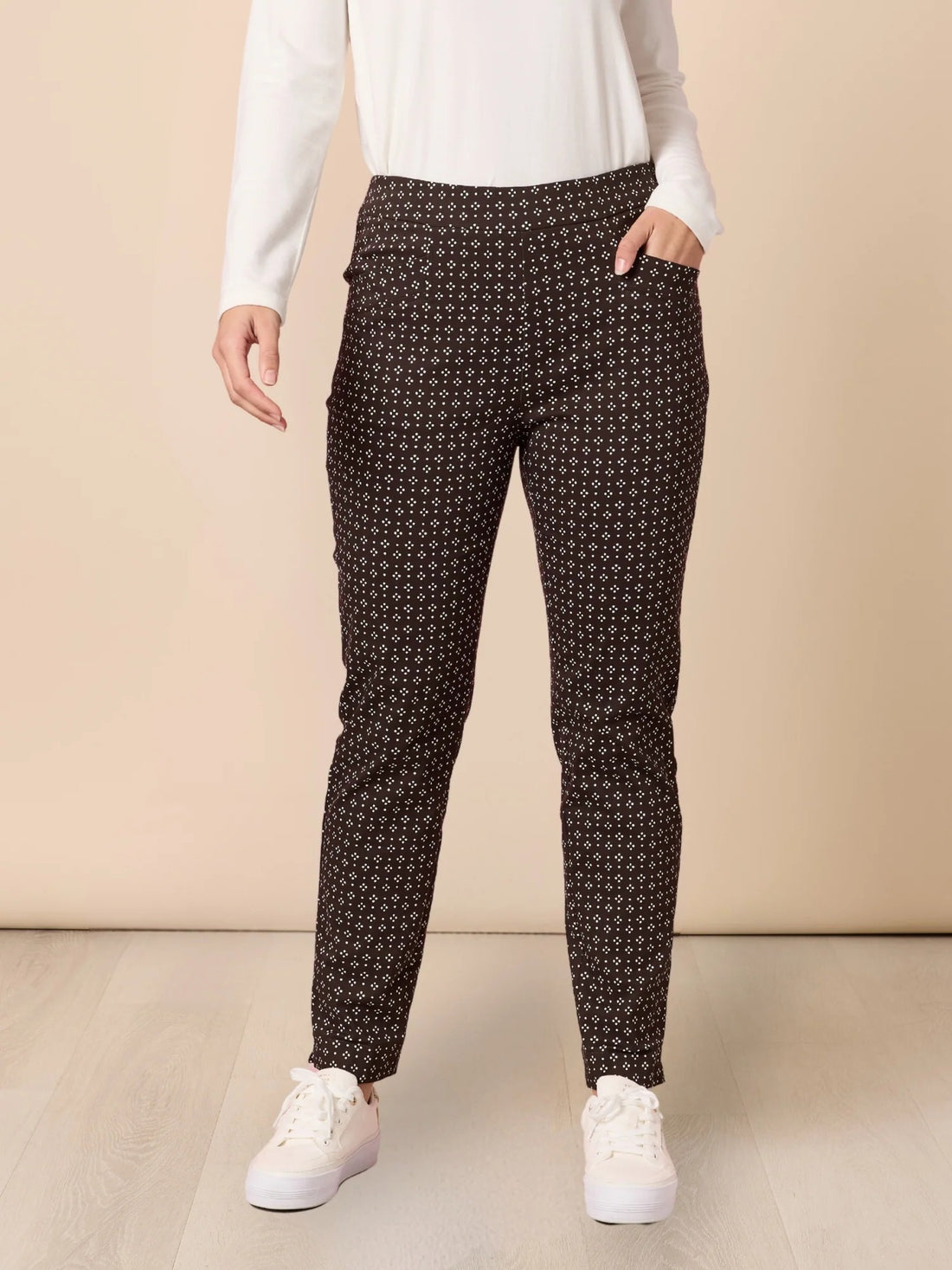 Women’s coffee brown slim fit pants with white micro print pattern, styled with white top and sneakers, front view product image from Showies Boutique Adelaide