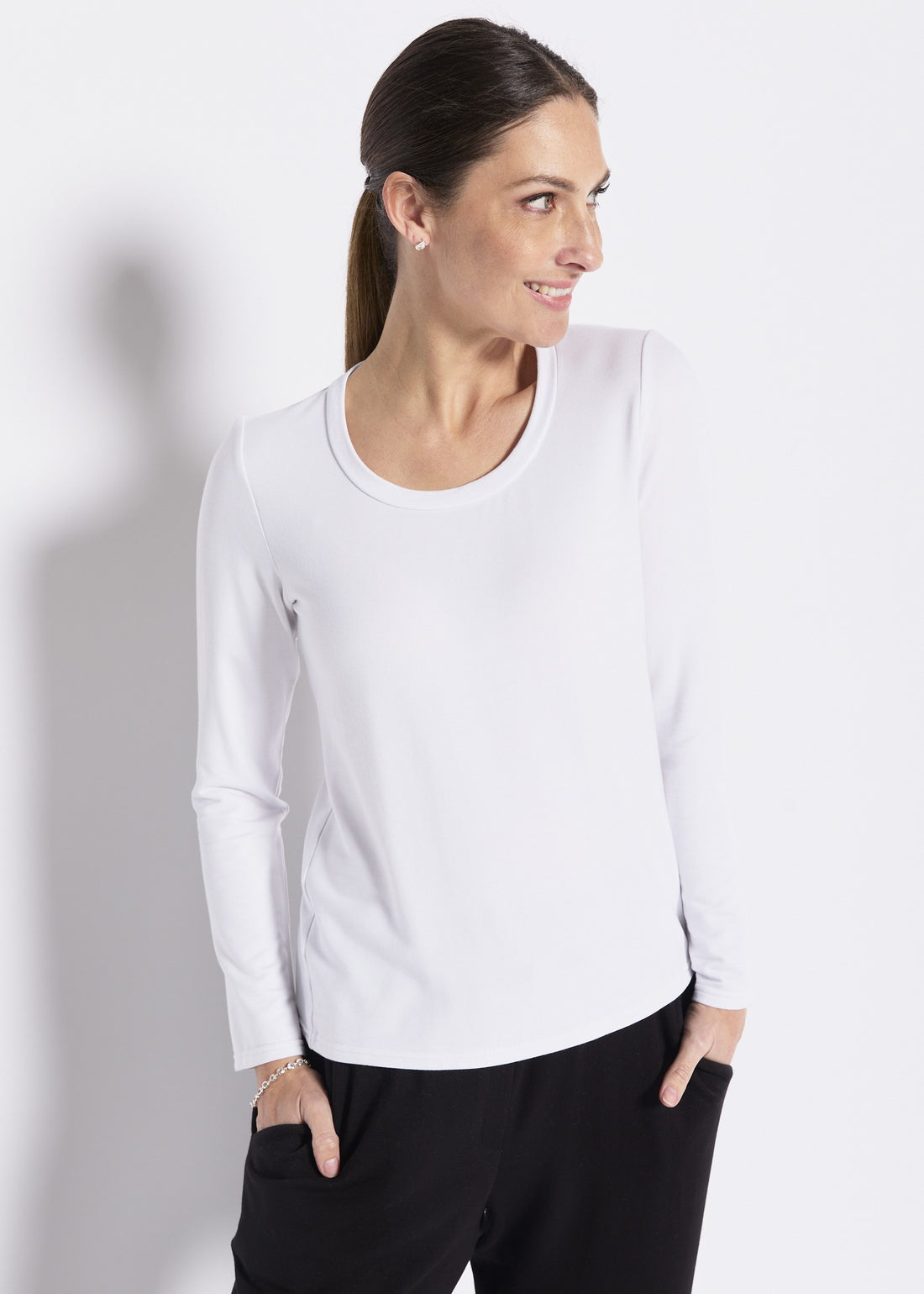 Woman wearing a black long sleeve crew neck top with grey lounge pants on a light background