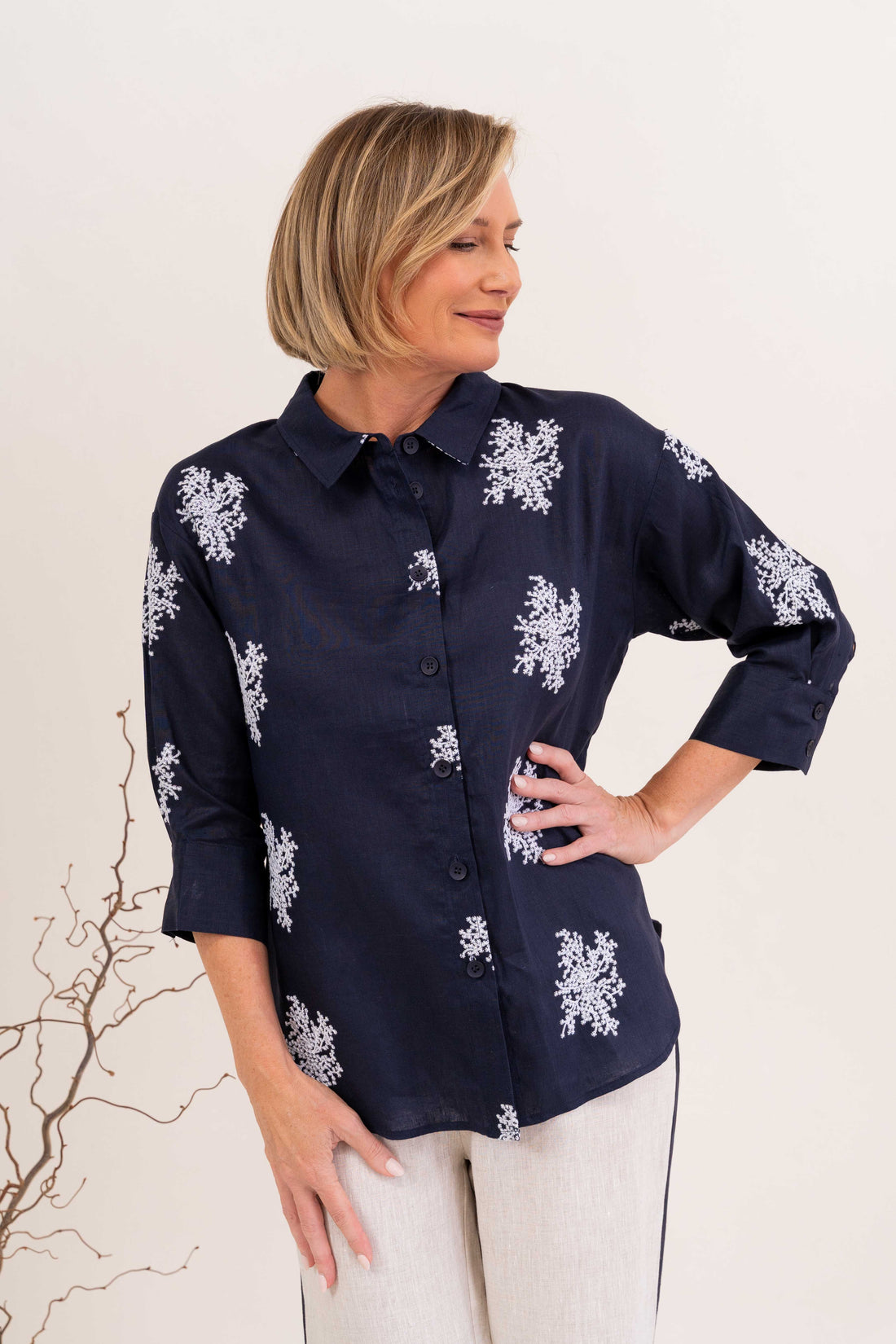 Navy embroidered linen shirt featuring white floral embroidery, classic collar, button-front closure, and three-quarter sleeves for an elegant everyday look.